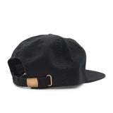 Black cap with a brown leather strap on a white background