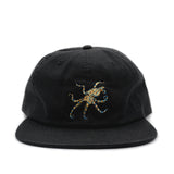 Black cap with a colorful blue ringed octopus design on a white background