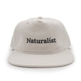 Bone colored cap with 'Naturalist' text on a white background