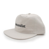 Bone colored cap with 'Naturalist' text on a white background