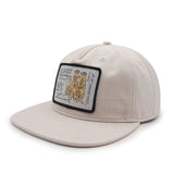 Beige cap with a patch featuring meerkats on and text on a white background