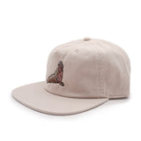 Side view of a beige cap with an elephant seal on a white background