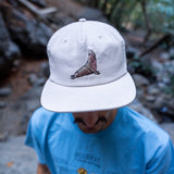 Person wearing a white cap with an elephant seal design outdoors