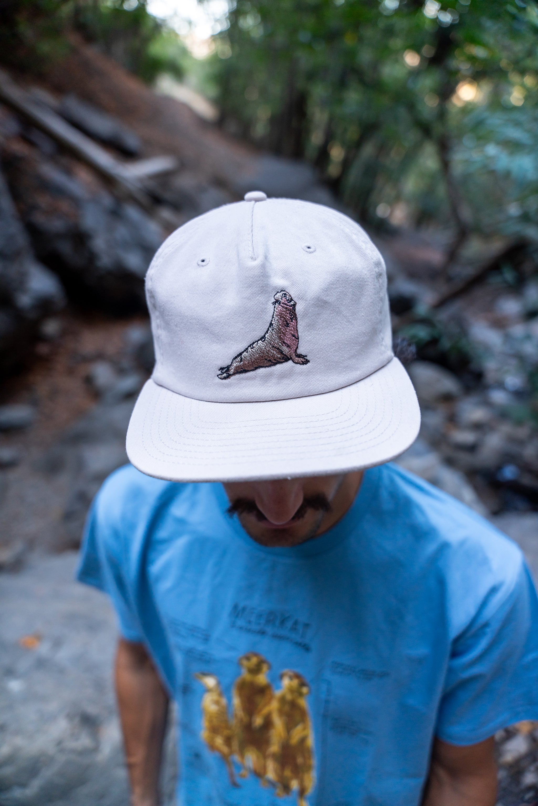 Person wearing a white cap with an elephant seal design outdoors