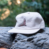 White cap with a northern elephant seal design on a rock with a blurred natural background