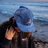 Woman wearing a blue coduroy hat with a northern elephant seal embroidered on it.
