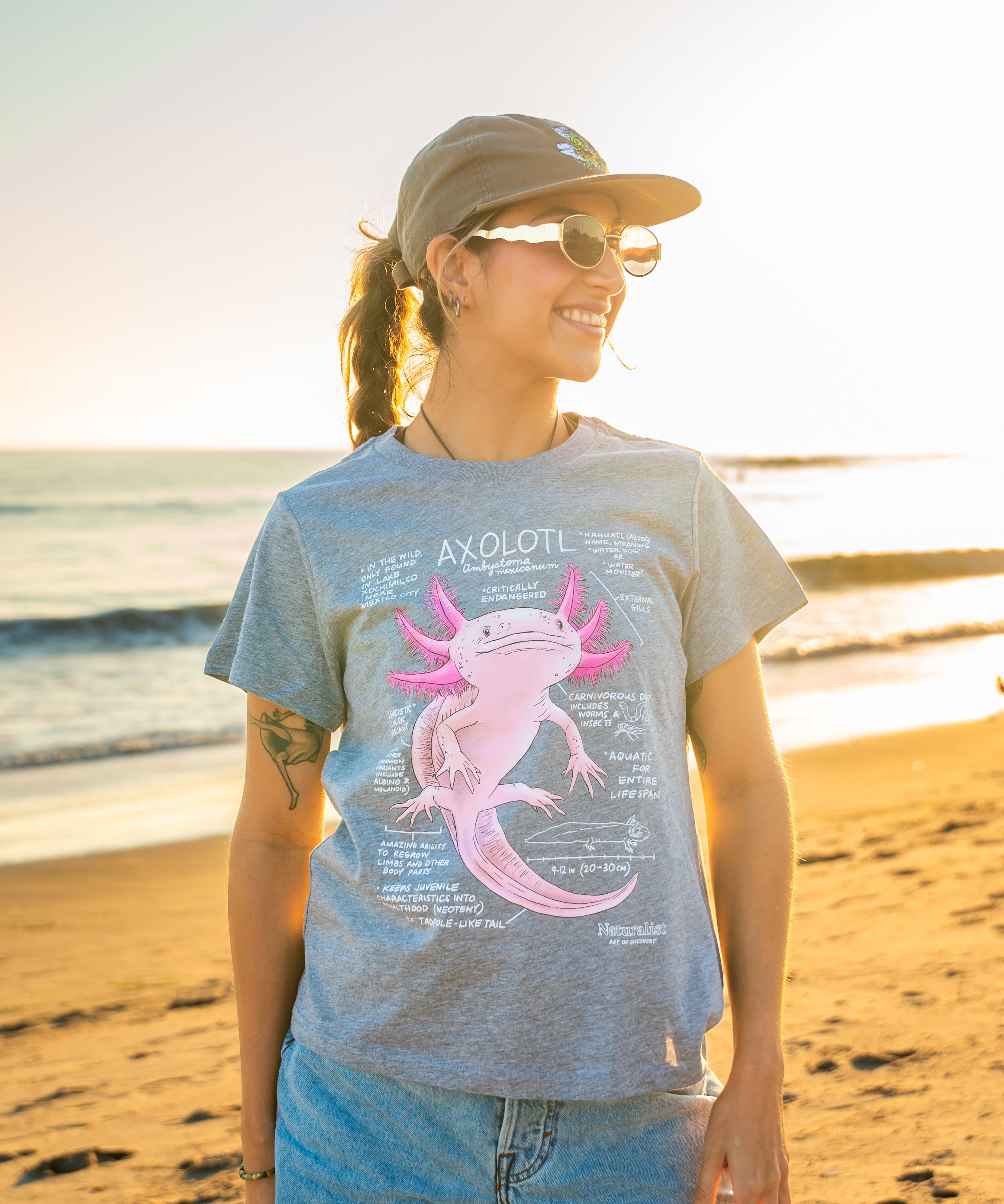 Person wearing a t-shirt with an axolotl graphic on a beach
