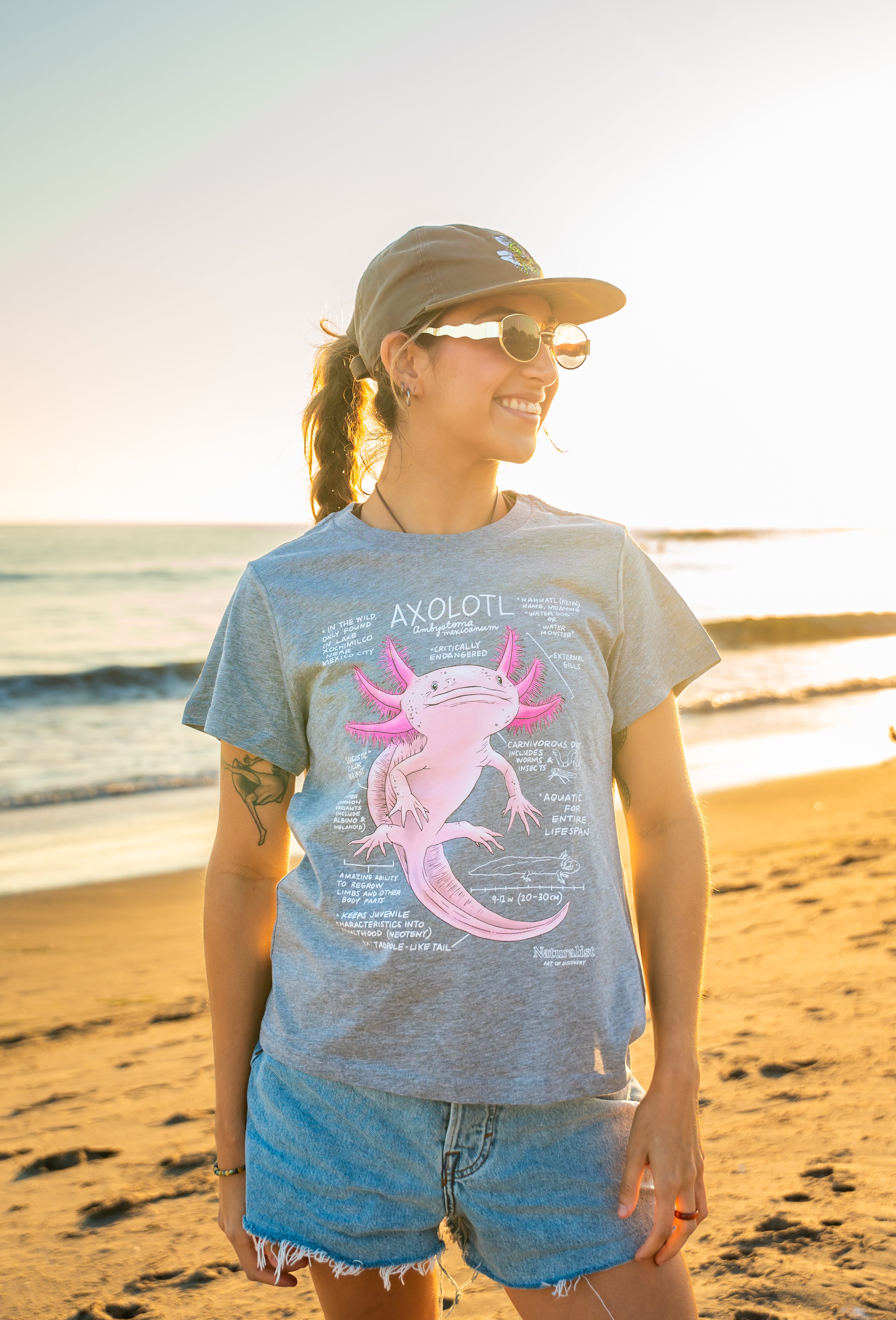 Person wearing a t-shirt with an axolotl graphic on a beach