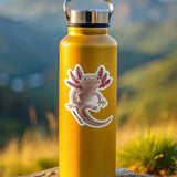 Yellow water bottle with a axolotl sticker on a rock with a mountainous background