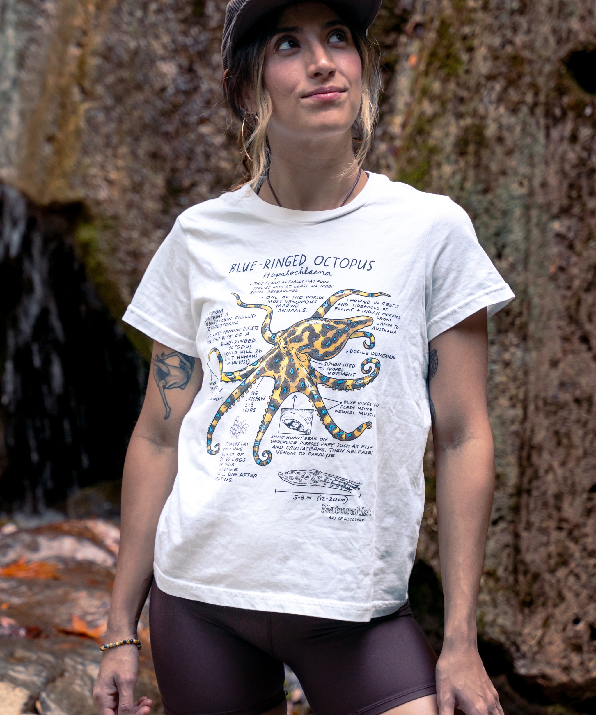 Woman wearing a white t-shirt with an octopus design outdoors.