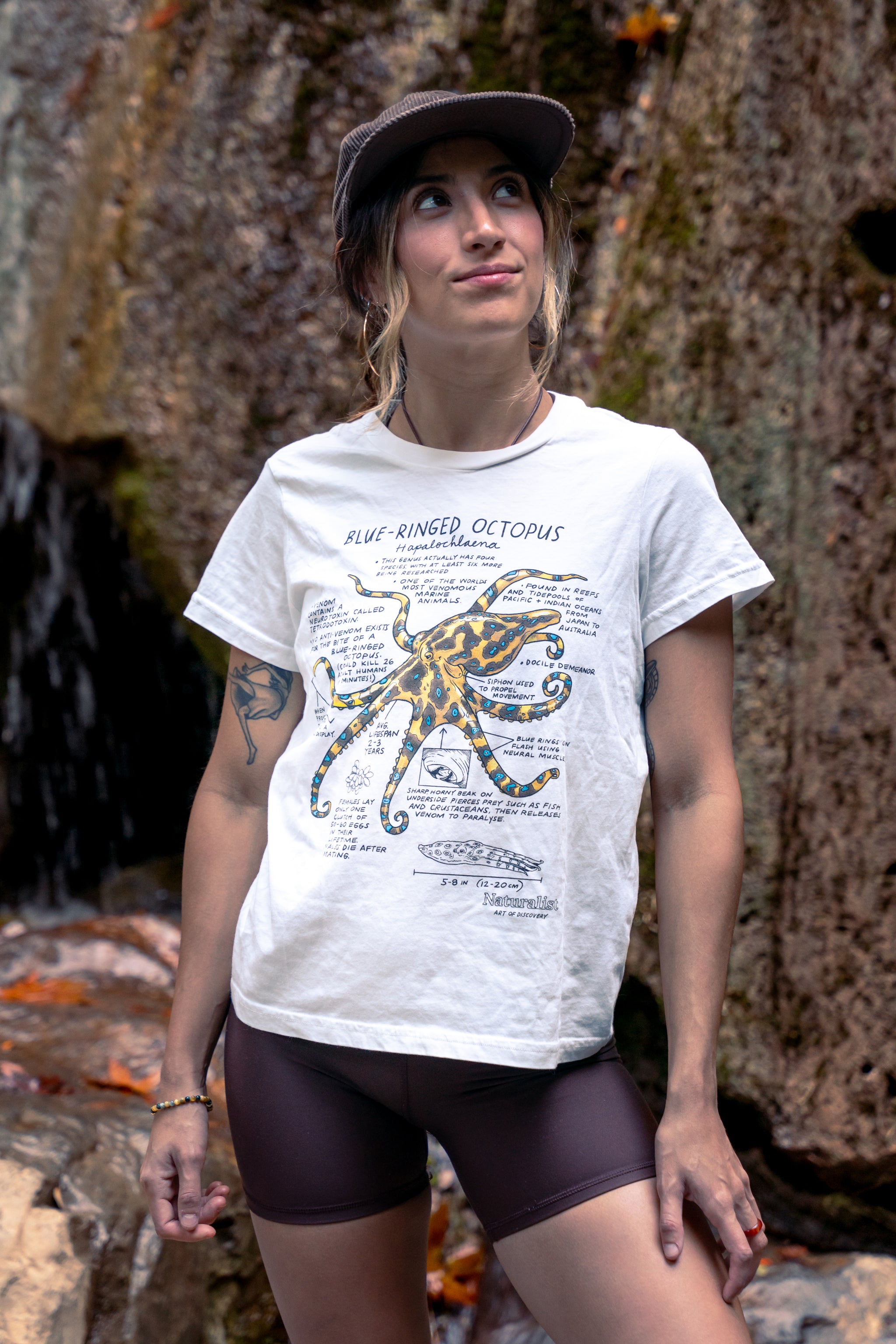 Woman wearing a white t-shirt with an octopus design outdoors.