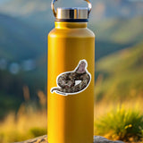 Yellow water bottle with a gaboon viper  sticker on a rock with a mountainous background