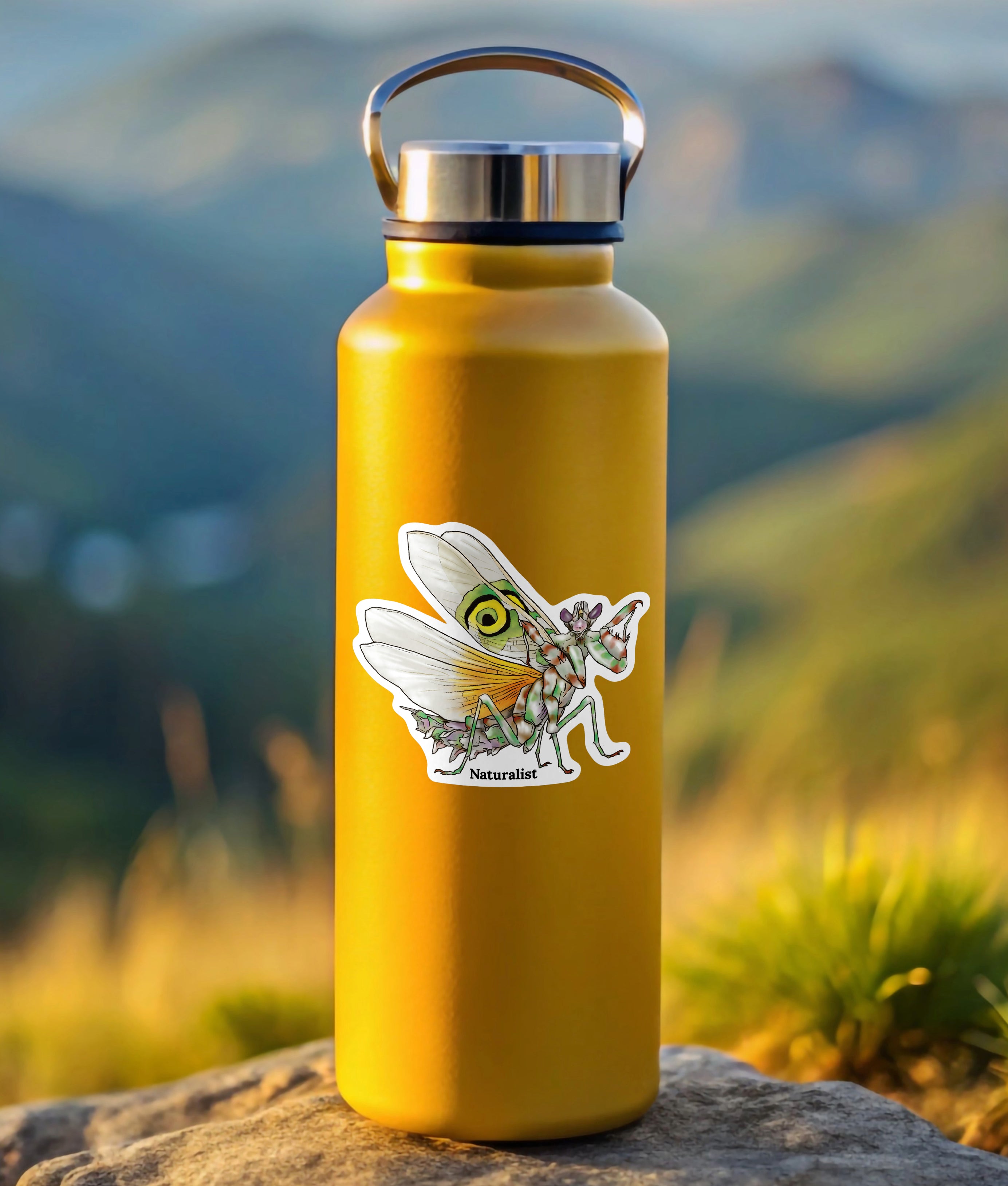 Yellow water bottle with a sticker of a praying mantis on a rock with a mountainous background