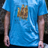 Person wearing a blue t-shirt with a graphic design of meerkats outdoors.