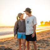 Two people standing on a beach at sunset