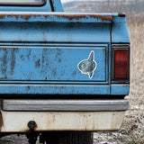 Rustic blue truck with an ocean sunfish decal on the back, outdoors.